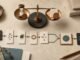 Overhead editorial still life of a balance scale, hourglass, gears and modular workflow cards representing AI automation costs and returns.