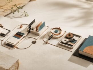 A warm editorial still life showing modular workflow components connected from source materials through review tools to a finished teal-bound deliverable.